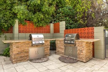 A backyard barbecue area with two grills and two bbqs