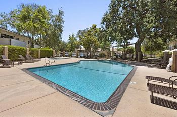 A swimming pool with chaise lounge chairs and trees