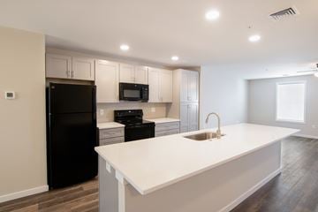 Middletown townhouse for rent - A kitchen with a black refrigerator, white countertops, and a microwave above the stove.