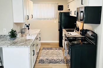 A kitchen with black appliances and white cabinets