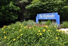 Ann Arbor apartment for rent - A blue sign that says "The Highlands" is surrounded by greenery and yellow flowers.