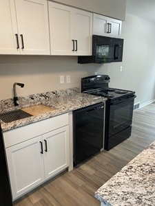 A black stove and oven in a kitchen with white cabinets