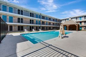Houston apartment for rent - A swimming pool is surrounded by sun loungers in front of a building.