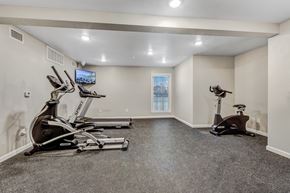 Houston apartment for rent - A spacious home gym with a television and exercise equipment.