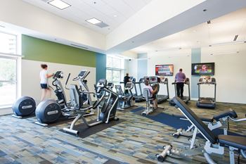 A gym with people working out and exercise equipment.