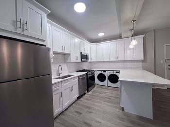 A modern kitchen with white cabinets and a stainless steel refrigerator.