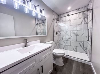 A bathroom with a white sink, toilet, and glass block shower.