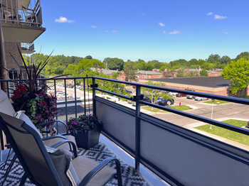 A balcony with a view of a parking lot and trees