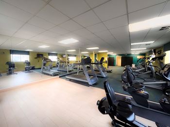 A gym with cardio equipment and weights on the floor