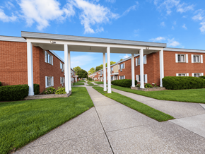 Brookpark apartment for rent - A long white covered walkway leads to a building with a white roof.