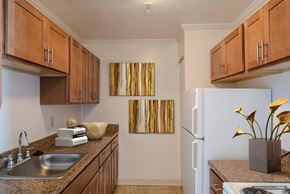 Parma apartment for rent - A kitchen with brown cabinets and a painting on the wall at Hummingbird Pointe & The Gardens, Parma