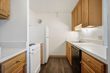 Parma Heights apartment for rent - A kitchen with wooden cabinets and white appliances.