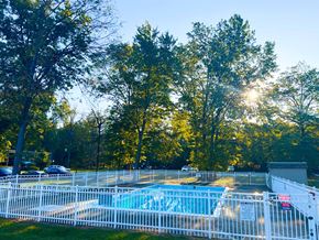 Willoughby apartment for rent - A pool surrounded by a white fence with trees in the background.