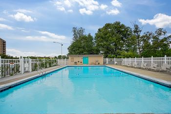 A large swimming pool with a blue water and white fence around it.