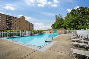 A swimming pool surrounded by chairs and apartment buildings.