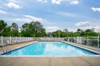 A large outdoor swimming pool surrounded by a white fence.