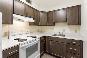 Cincinnati apartment for rent - A kitchen with white and brown cabinets and a white stove top oven.