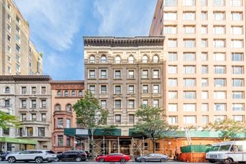 New York apartment for rent - A red car is parked in front of a building with a green awning.