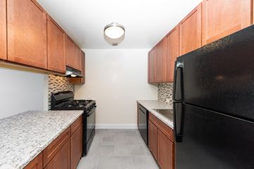 New York apartment for rent - a kitchen with black appliances and granite counters and wood cabinets