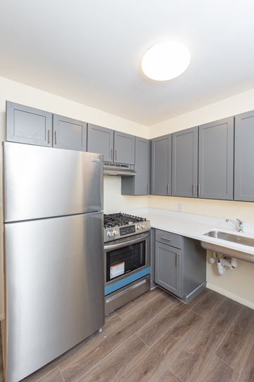 New York apartment for rent - a kitchen with stainless steel appliances and gray cabinets