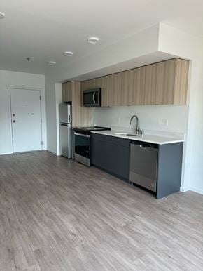 Seattle apartment for rent - a kitchen in an empty apartment with a sink and refrigerator at Junction Central, Seattle, WA