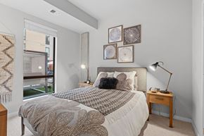 Bloomington apartment for rent - A bedroom with a large bed and a window overlooking a balcony.