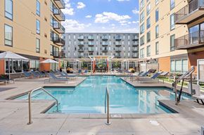 Bloomington apartment for rent - A large swimming pool surrounded by lounge chairs and umbrellas in a sunny courtyard.