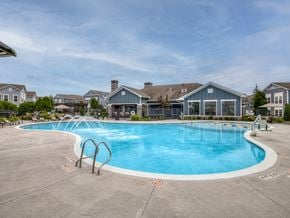 Rogers apartment for rent - A large outdoor swimming pool surrounded by a concrete patio and residential buildings.