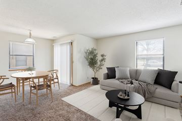 Wichita apartment for rent - A living room with a grey couch, a wooden dining table with chairs, and a small tree.