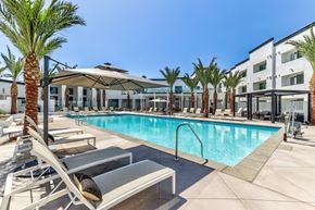 Redlands apartment for rent - A pool surrounded by palm trees and lounge chairs.