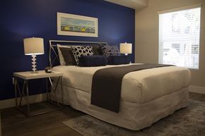 Redlands apartment for rent - a bedroom with a blue accent wall and a white bed with a black and white comfort at The Crossings at Redlands, California, 92374