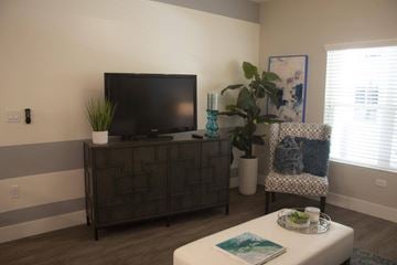 Redlands apartment for rent - A living room with a television on a cabinet and a chair with a blue and white pattern.