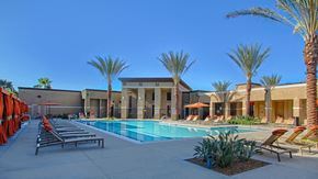 Redlands apartment for rent - Dog-Friendly Apartments in Redlands, CA - Circa 2020 - Swimming Pool Lined with Chaise Lounges, Umbrellas, Private Cabanas with Drapery, Palm Trees Landscape Area, and Stucco-Exterior Building View.