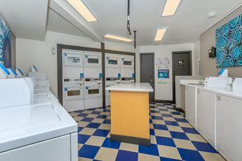 A laundry room with white machines and a yellow counter