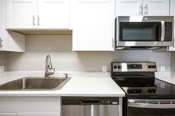 A kitchen with white cabinets and stainless steel appliances