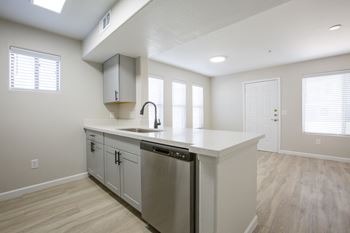 A kitchen with white cabinets and a large island with a stainless steel dishwasher