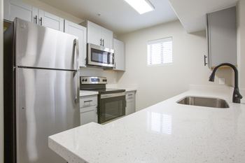A kitchen with white cabinets and a white counter top