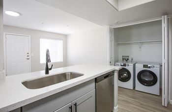A kitchen with a sink and a washer and dryer