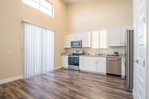 Queen Creek apartment for rent - Model kitchen at Village Green of Queen Creek with wood-style flooring, modern appliances and a sliding glass door
