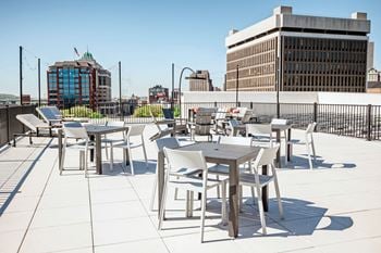 A rooftop patio with tables and chairs and a city in the background