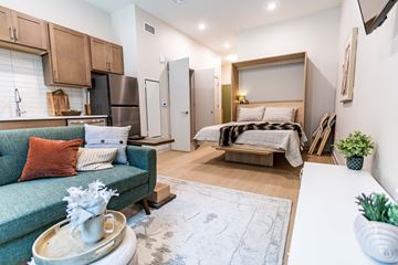 Troy apartment for rent - A living room with a green couch and a bed in the background.