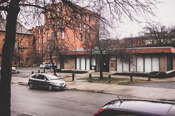 Troy apartment for rent - A car is parked on the side of a street in front of a building.