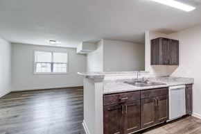 Newport News apartment for rent - A kitchen with dark wood cabinets and a white countertop. at Ada Park Apartments, Newport News, VA