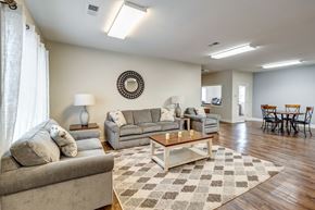 Newport News apartment for rent - A living room with a couch, a coffee table, and a dining table. at Ada Park Apartments, Newport News, VA