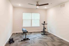 Henrico apartment for rent - A room with a ceiling fan, a window, and exercise equipment. at Bickerstaff Crossing Apartments, Henrico