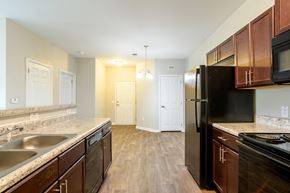 Hendersonville apartment for rent - Open-concept kitchen with breakfast bar, double sink, and view into dining and entry area, finished with wood-style flooring at Cedar Terrace Apartments Hendersonville