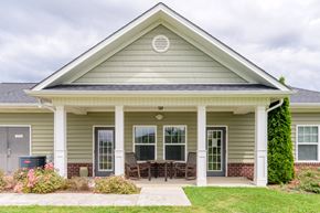 Hendersonville apartment for rent - Inviting clubhouse exterior with covered front porch, patio seating, and manicured landscaping at Cedar Terrace Apartments in Hendersonville