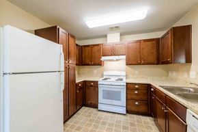 Rolesville apartment for rent - A kitchen with brown cabinets and a white refrigerator at Granite Falls Apartments, Rolesville, NC