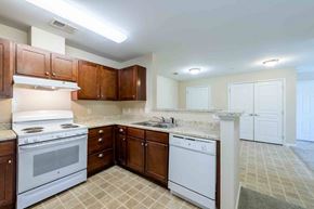 Rolesville apartment for rent - A kitchen with white appliances and brown cabinets at Granite Falls Apartments, North Carolina