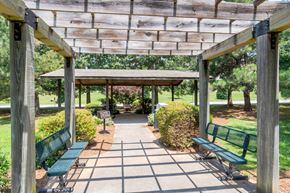 Statesville apartment for rent - A wooden pergola with green benches is in a park.at Greylin Ridge Apartments, Statesville